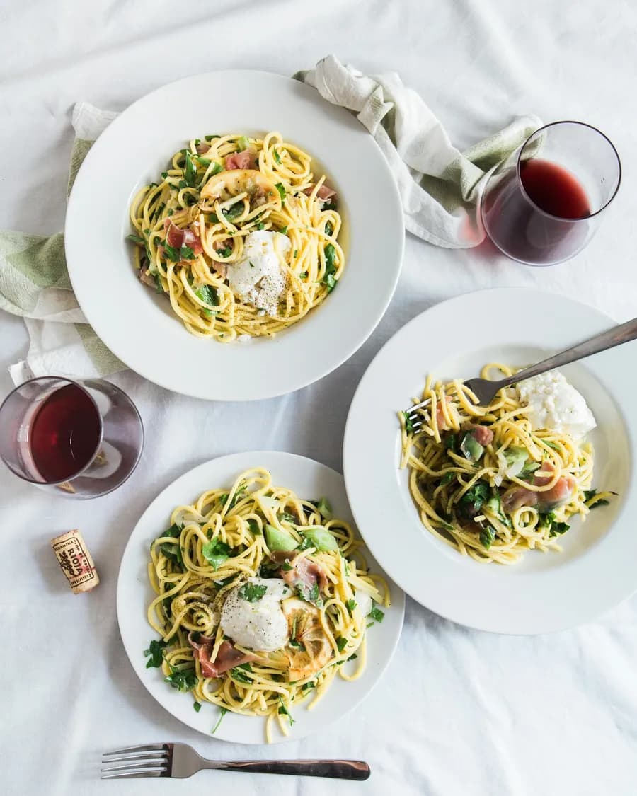 Plates of spaghetti and glasses of wine on a dinner table, seen from above